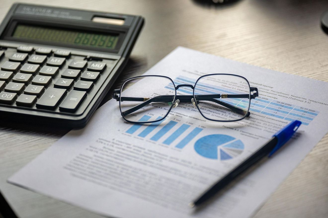 Rekenmachine, bril en financiële overzichten op een bureau